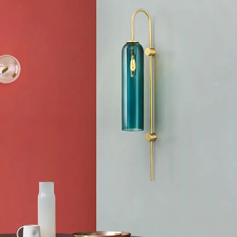 Modern gold and black orb wall lamp featuring a teal glass cylinder sconce with brass frame and exposed filament bulb