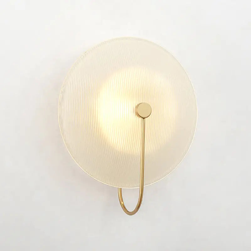 Modern gold and black wall lamp with circular textured frosted glass shade and minimalist metal arm for living rooms