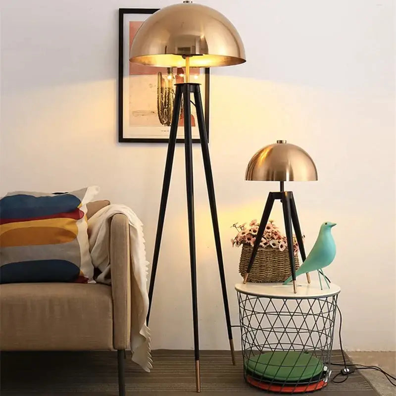 Modern gold and black decorbites coyote tripod floor lamp with brass dome and warm glowing light for living room decor