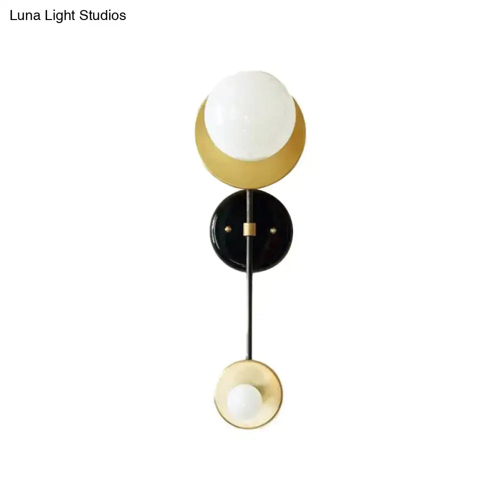 Modern gold and black wall sconce with opal glass shade featuring a white globe and crescent design for bedroom lighting