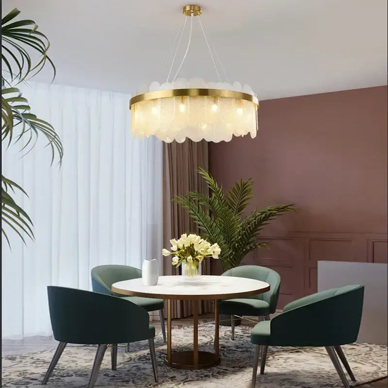 Modern gold and blue glass chandelier with scalloped panels provides a warm lighting solution for dining table settings