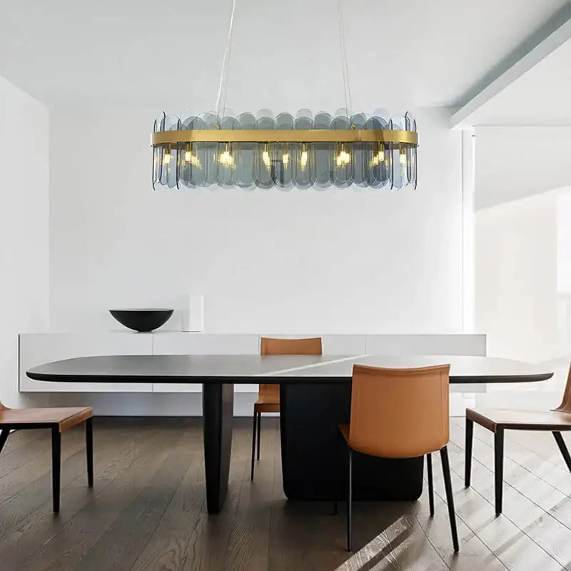 Modern glass chandelier with gold-toned metal frame and blue glass panels enhancing the dining experience lighting solution