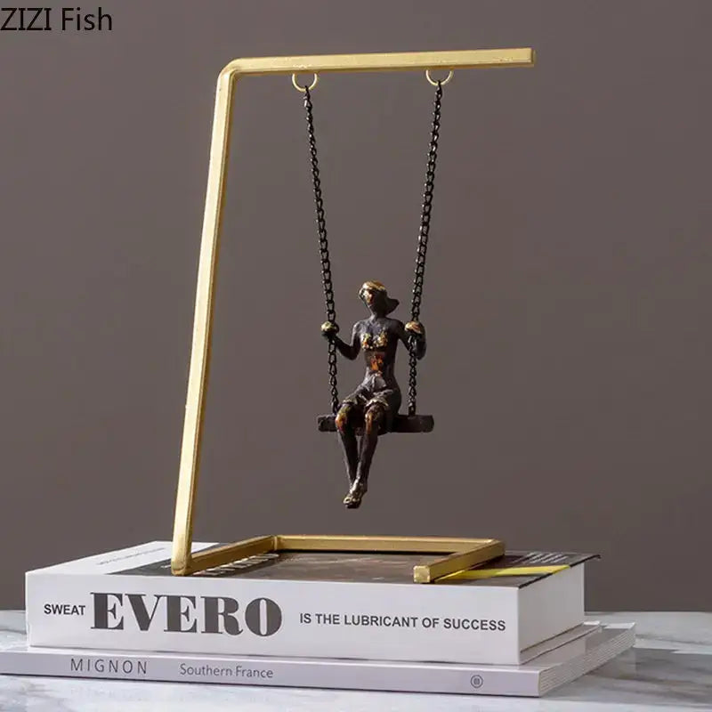Bronze figurine of a woman sitting on a black chain suspended swing in a gold-toned modern golden swing metal sculpture decorbites decor