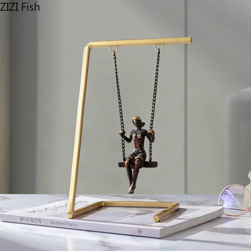 Bronze woman figurine sitting on a black chain swing in a gold-toned golden swing metal sculpture decorbites living room decor