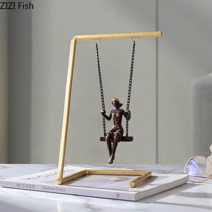 Bronze woman figurine sitting on a black chain swing in a gold-toned golden swing metal sculpture decorbites living room decor