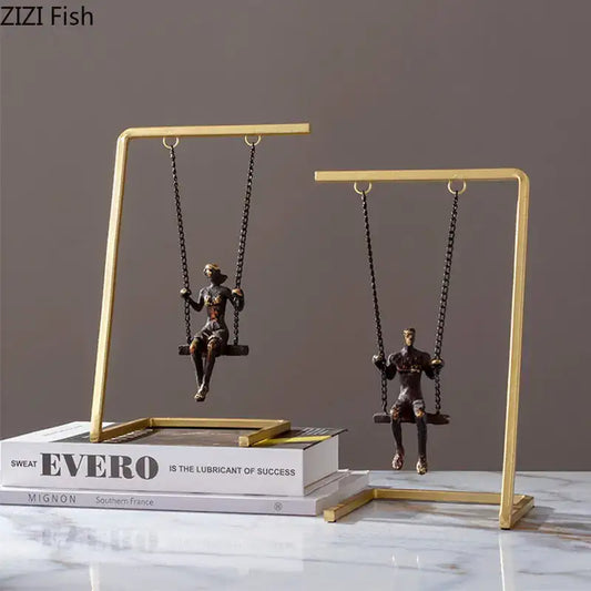 Modern gold and bronze swing metal sculpture featuring two bronze figurines on a gold-toned swing decorbites golden swing