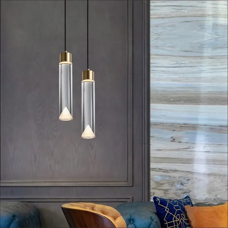 Two modern pendant lights with clear crystal copper cylinders and gold tops featuring white conical bulbs for dining room decorbites clear crystal