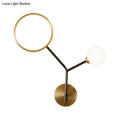 Modern brass-finished wall sconce lamp with circular ring and spherical globe for bedroom lighting use