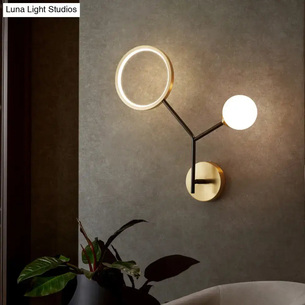 Modern gold and cream glass wall sconce lamp with gold base black arms circular ring light and globe bulb for bedroom use