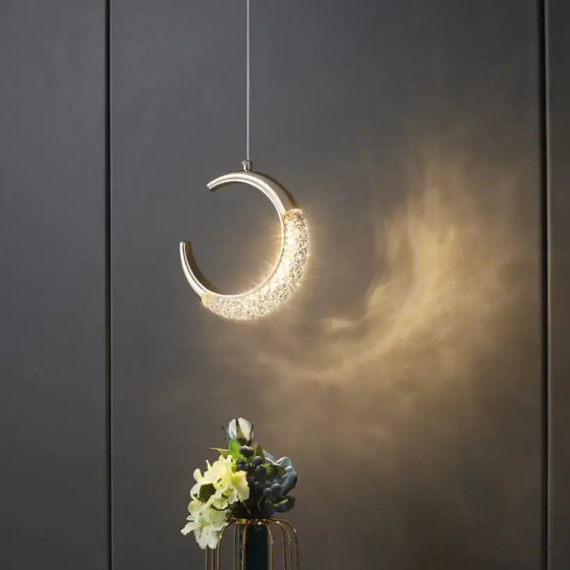 Modern gold and crystal oval bedside pendant light with metallic finish and sparkling crystals emitting warm glow