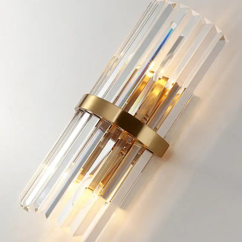 Modern gold and crystal wall light with vertical crystal rods and polished metal band for elegant living room decorbites crystal wall