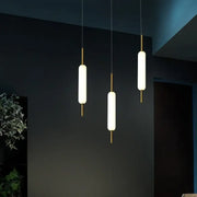 Three modern gold and frosted glass led pendant chandelier lights with cylindrical shades for living room use