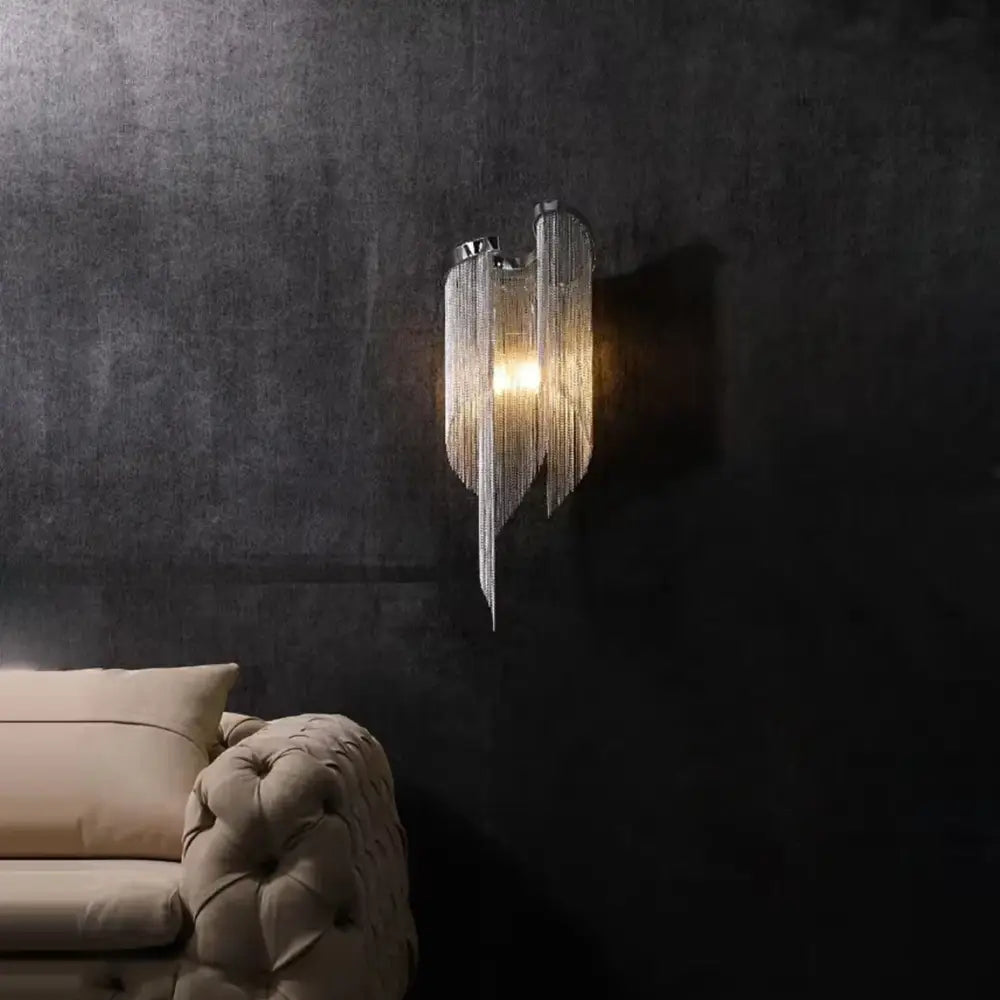Modern gold and gray glass wall lamp with sleek chrome finish and cascading chains emitting warm golden glow