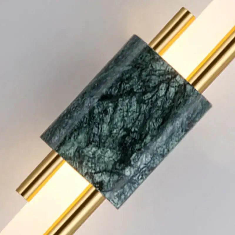 Modern gold and green marble wall lamp featuring dark green veined marble set between polished gold rods for bedroom use