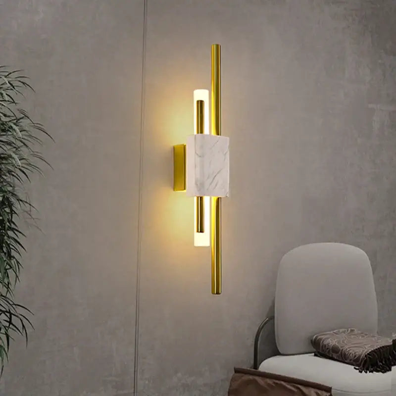 Modern gold wall lamp with rectangular white marble accent and two vertical cylindrical lights for bedroom sconce