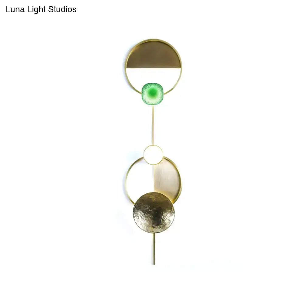 Modern gold and green orbit wall sconce with geometric metal circles and glowing green glass wall lamp for bedroom