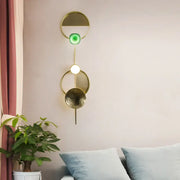 Modern gold and green orbit wall sconce with layered concentric rings glowing as a stylish bedroom wall lamp