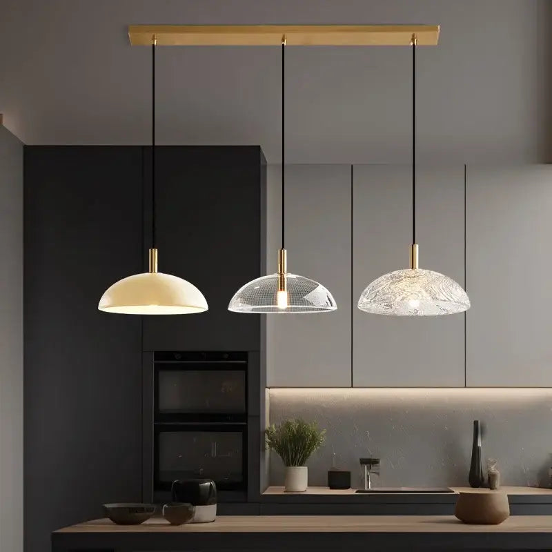 Three modern pendant lights with gold-finished fixtures and glass pendant shades for kitchen dining room lighting