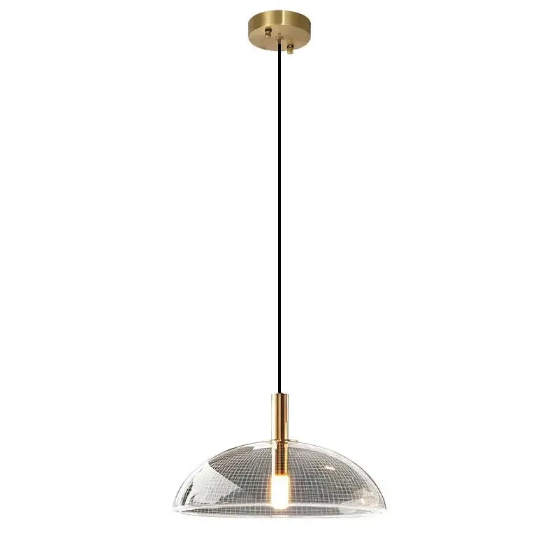 Modern gold pendant light with a brass ceiling mount and textured clear glass pendant featuring a grid pattern