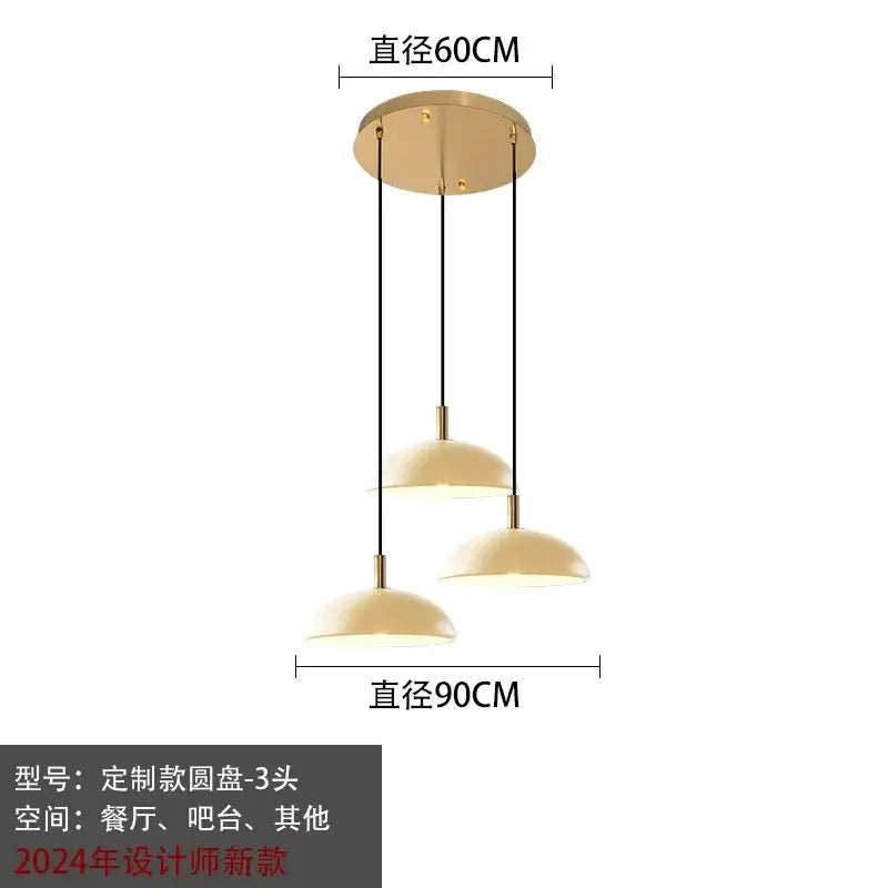 Modern gold pendant light with three cream dome glass pendant shades suspended by black cords for kitchen dining room