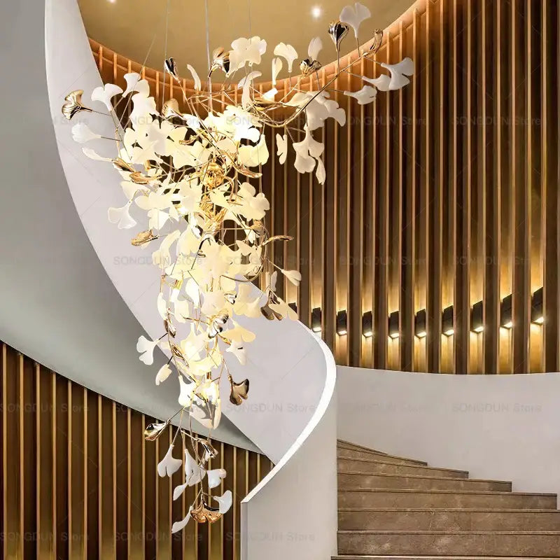 Elegant modern gold and white gingko leaf ceramic chandelier hanging above a staircase by decorbites gingko leaf design