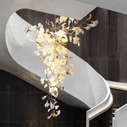 Elegant modern gold and white gingko leaf ceramic chandelier by decorbites hanging above a staircase