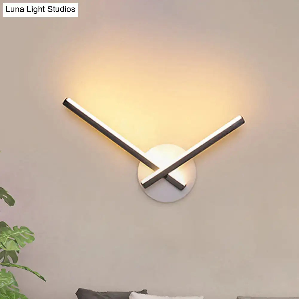 Modern gold angular wall lamp with intersecting chrome rods and warm white light on a circular white base wall lamp