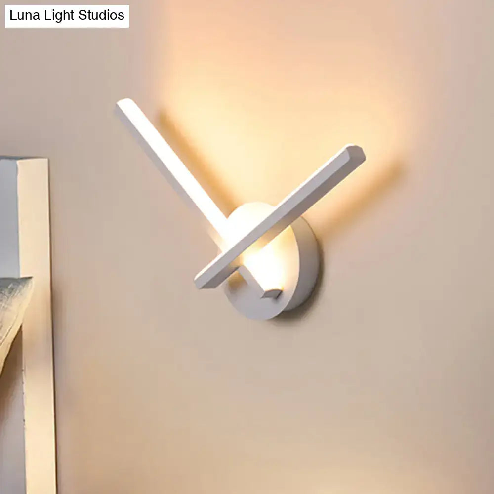 Modern gold angular wall lamp with sleek white arms emitting warm white light for bedroom lighting