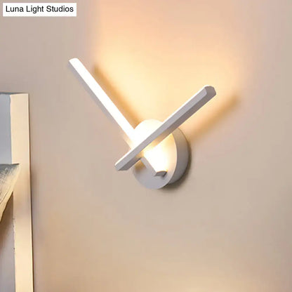 Modern gold angular wall lamp with sleek white arms emitting warm white light for bedroom lighting
