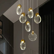 Modern gold attic crystal chandelier with clear bubble-filled glass discs hanging from thin cords for dining room lighting