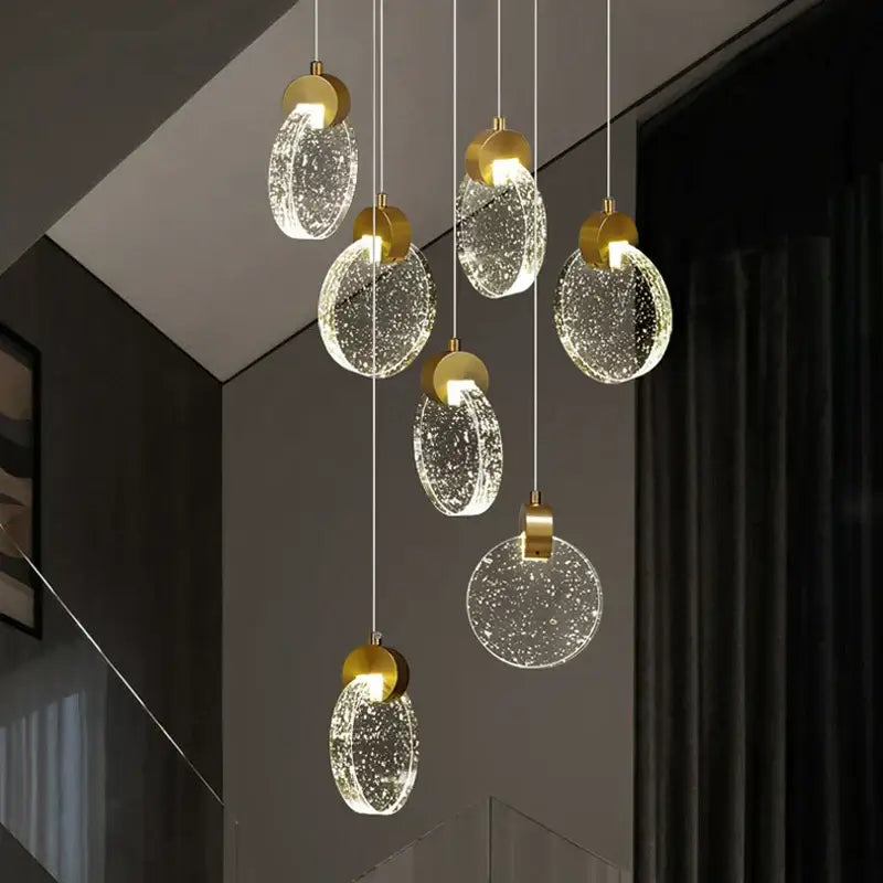 Modern gold attic crystal chandelier with clear bubble-filled glass discs hanging from thin cords for dining room lighting