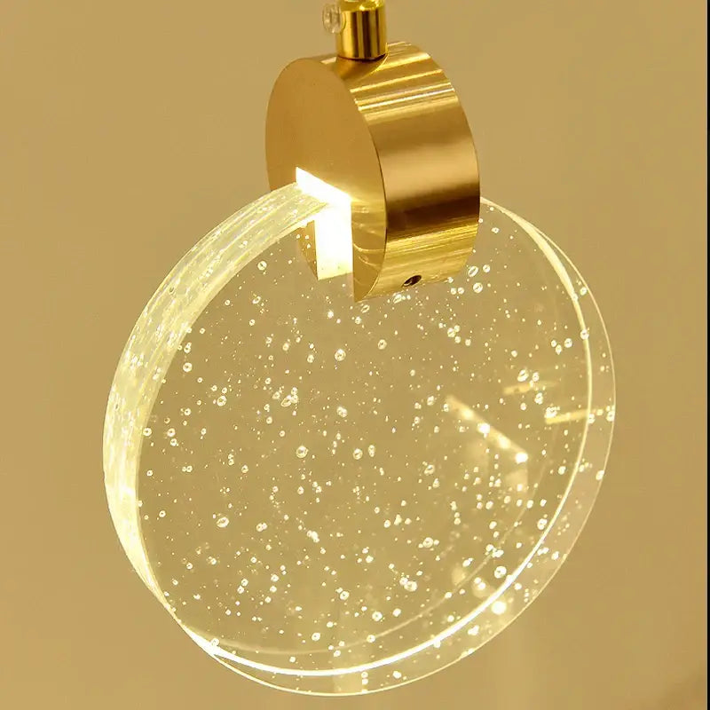 Modern gold attic crystal chandelier featuring a circular metal fixture and bubble-filled glass diffuser for dining room
