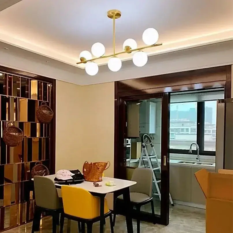 Modern gold bean glass chandelier featuring six white spherical glass bulbs for dining room linear lighting