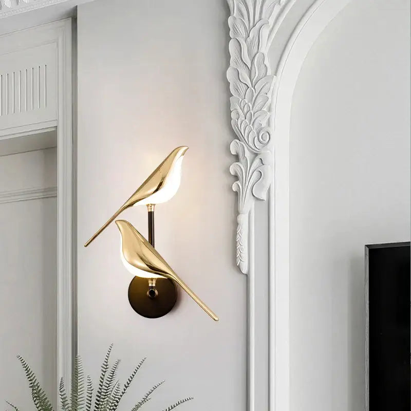 Modern gold-toned wall sconce with decorbites bird design and warm led light for bedroom accent lighting