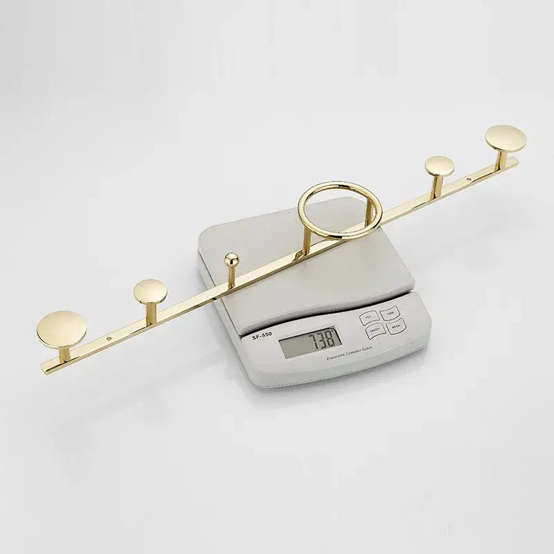 Gold-colored metal towel hook set with five circular hooks and central ring displayed on electronic scale