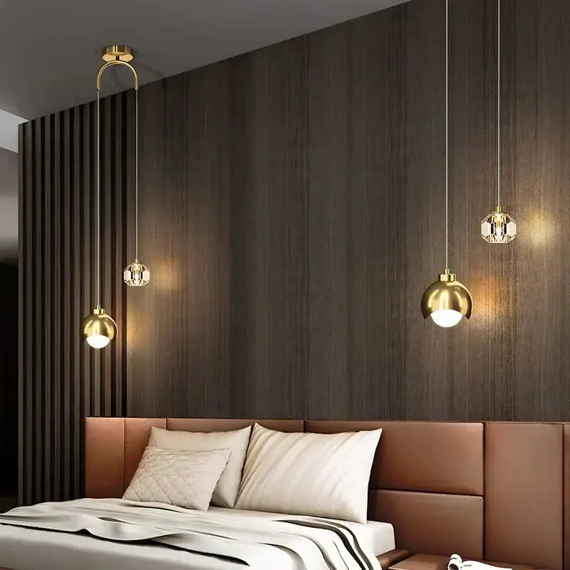 Three modern gold and black crystal linear pendant lights with metal fixtures hang above a bed in dining room setting