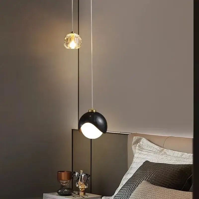 Two modern pendant lights with gold and black finishes feature a crystal globe and matte dome with bulbs included color options