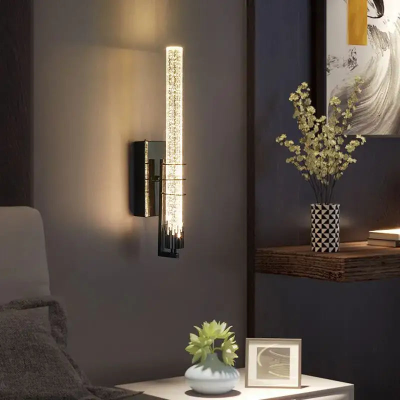 Modern gold and black crystal wall sconce with vertical illuminated glass tube featuring embedded crystal elements