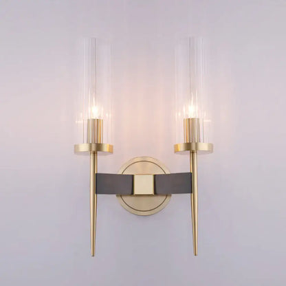 Modern gold wall lamp with black fluted glass cylinders and central dark gray leather strap for bedroom sconce lighting