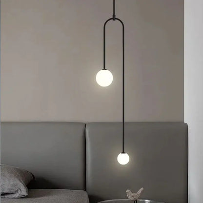 Black minimalist pendant light with two frosted glass globe bulbs and curved metal detailing for dining room use