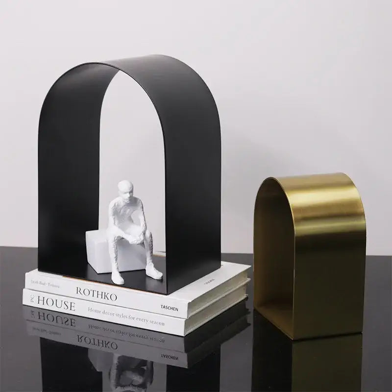 Modern gold and black golden arches metal sculpture bookend featuring a black arched bookend with white figure and gold counterpart