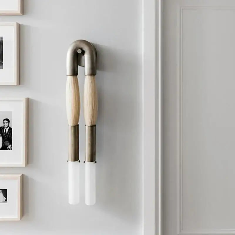 Modern gold and black horsehair wall lamp with a brushed metal u-shaped top, wood handles, and frosted glass shades