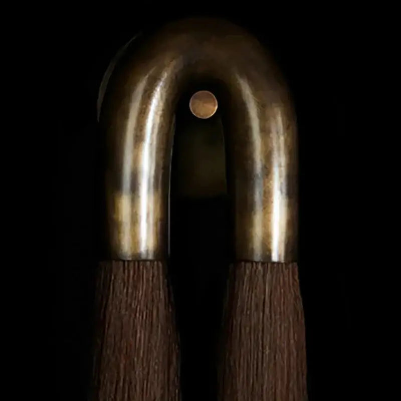 A bronze metal hair comb with a curved u-shaped design and dark brown wooden bristles decorbites horsehair wall lamp decor