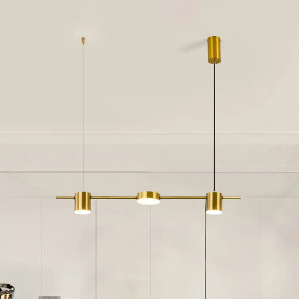 Gold-toned modern pendant light with three cylindrical fixtures on a bar, featuring warm white light and rotatable shades