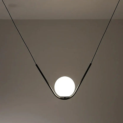 Minimalist pendant light with a sleek black metal frame and spherical glass bulb from decorbites golden black perle collection