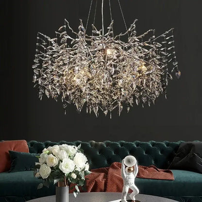 Modern gold branch crystal chandelier with intricate leaf design and glass elements above dark green velvet sofa