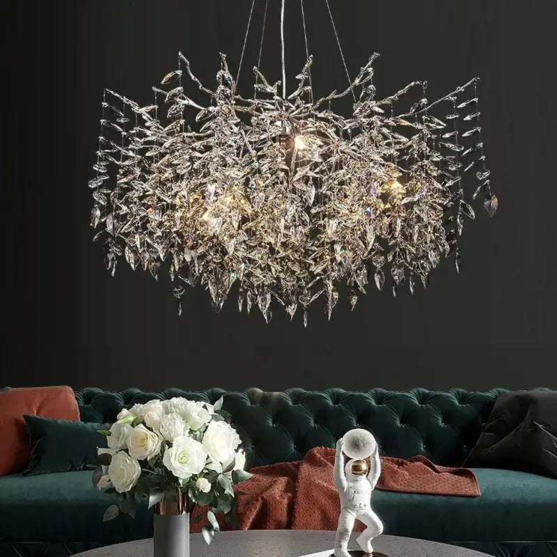 Modern gold branch crystal chandelier with intricate leaf design and glass elements above dark green velvet sofa