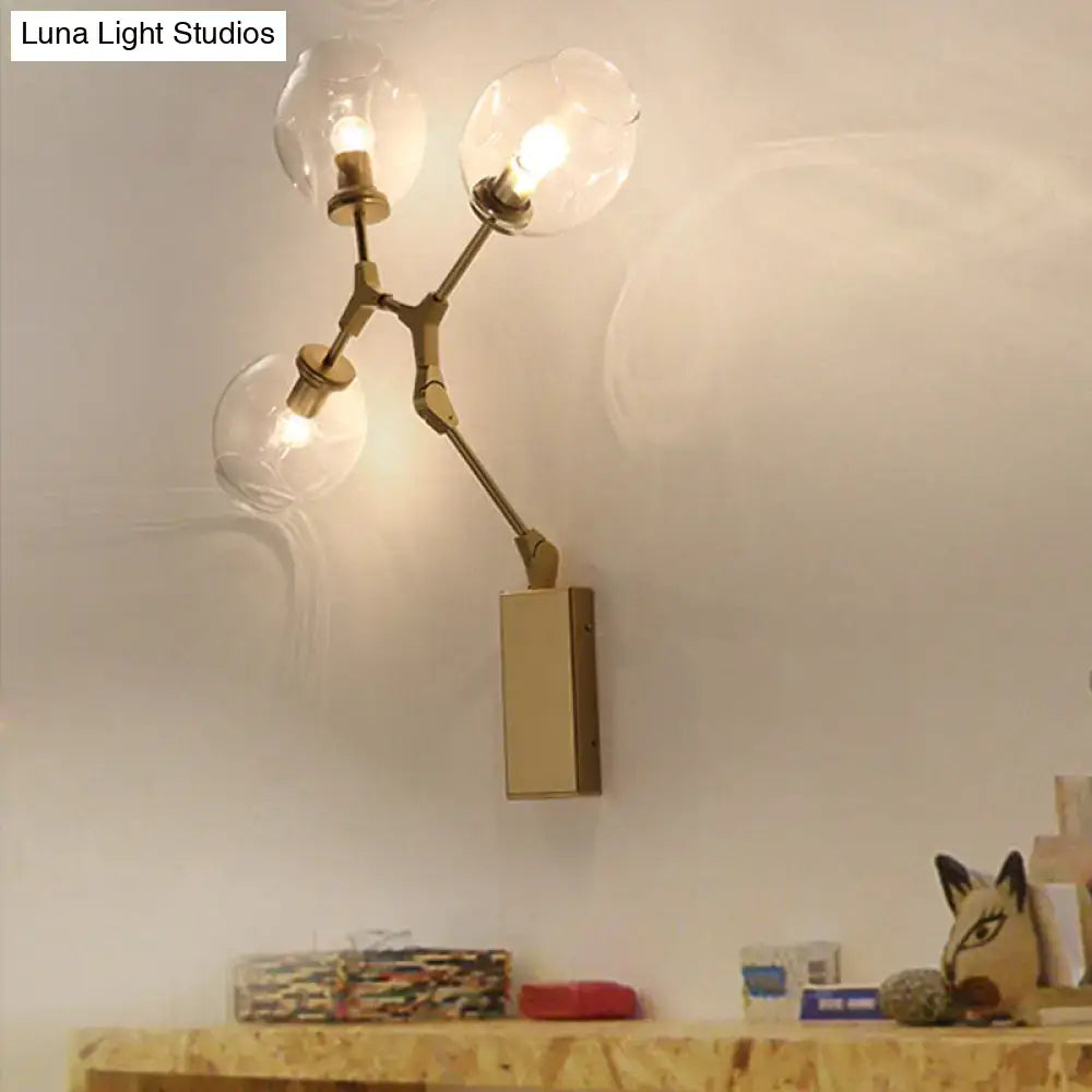 Brass-finished modern gold branch wall lamp with three clear glass globe shades for living room lighting