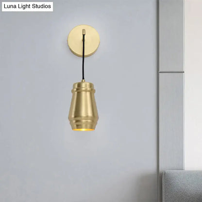 Modern gold brass bedroom wall sconce with a brass-finished metal shade and cylindrical inch fixture design