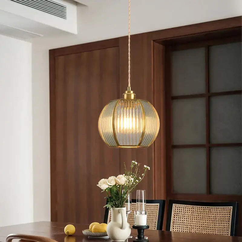 Modern gold brass glass restaurant light with ribbed glass globe and warm brass finish hanging from twisted cord